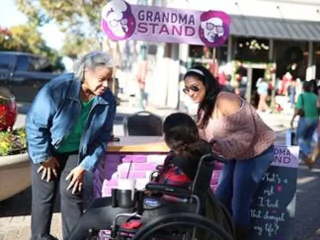 Grandma visits with two women, one in a wheelchair, in Downtown McKinney.